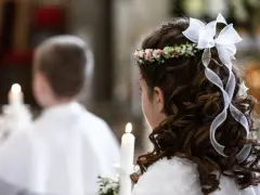 Dziewczynka z wiankiem na głowie i wstążkami we włosach trzyma świecę. Obok niej chłopiec, też z zapaloną świecą. To ważny dzień, biały tydzień.