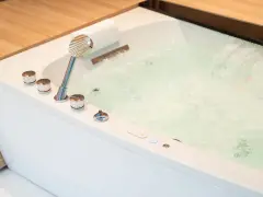 Bain bouillonnant avec jets d'eau et douchette chromée, prêt pour un moment de détente dans ce spa balnéo.