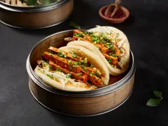 Pierożki baozi z tofu i warzywami, podane w bambusowym parowniku.