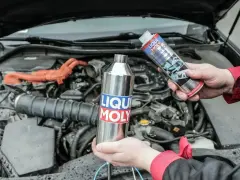 Dwie ręce trzymają produkty Liqui Moly, jeden metalowy, drugi w sprayu, gotowe do czyszczenia katalizatora w silniku samochodu.