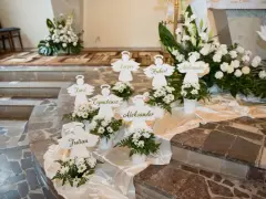 Urocze pomysły na dekoracje komunijne w kościele: aniołki z imionami dzieci i białe kwiaty tworzą magiczną atmosferę.