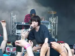 La chanteuse de Crystal Castles, Alice Glass, chante devant une foule. Un autre membre est derrière elle.