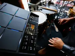Nowoczesny sampler perkusyjny Roland SPD-SX PRO gotowy do tworzenia rytmów. W tle widoczne elementy zestawu perkusyjnego.