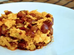 Deliciosa porción de duelos y quebrantos receta, con huevo revuelto y trozos de chorizo, servida en plato blanco.