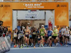 Zawodnicy przekraczają linię startu Maratonu Cracovia. Tłum kibiców z telefonami dokumentuje to wydarzenie.