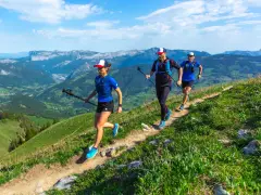 Trzy osoby uprawiające speed hiking na górskim szlaku, ciesząc się pięknymi widokami.