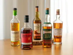 Fünf Flaschen gute Whiskey-Sorten: Glenfiddich, Glenallachie, Talisker, Cragganmore und Ardnahoe stehen auf einem Holztisch.