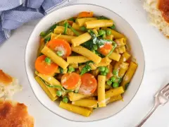 Makaron z mlekiem kokosowym i curry, z marchewką i groszkiem. Kremowy sos otula złociste rurki, tworząc aromatyczne danie.