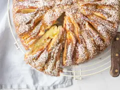 Deliziosa torta di mele in friggitrice ad aria, cosparsa di zucchero a velo, con una fetta tagliata che mostra la morbidezza dell'interno.