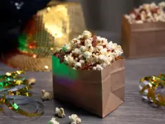 Festliga popcornboxar med bacon, redo för nyårsfirande. Glitterband och en paljetthatt i bakgrunden skapar en festlig stämning.