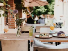 Leckeres Frühstück im 21 gramm Berlin: Toast mit Belag, Drinks & Blumen auf Holztisch.