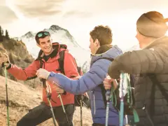 Trois randonneurs souriants, prêts pour une reconversion accompagnateur moyenne montagne, profitent du soleil couchant sur les sentiers.