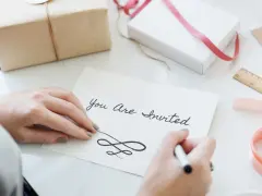 Ręce piszą zaproszenie "You Are Invited". Dowiedz się, jak napisać zaproszenie na urodziny po angielsku.