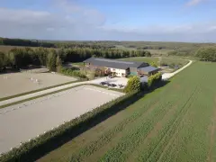 Vue aérienne d'une écurie avec manège et carrière de dressage. Le système de **carrière subirrigation** assure un sol parfait pour les chevaux.