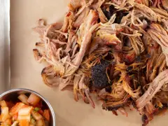 Zartes Pulled Pork, perfekt gegart, zeigt die ideale pulled pork kerntemperatur. Daneben eine Schale mit frischer Salsa.