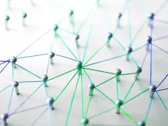 Netzwerk aus silbernen Pins und bunten Fäden auf weißem Untergrund.