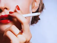 Labios rojos, uñas rojas y un cigarrillo. Una mujer se lleva el cigarrillo a la boca, quizás pensando que la nicotina adelgaza.