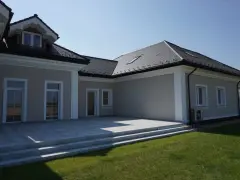 Nowoczesny dom z tarasem i trawnikiem. Elegancki gzyms podkreśla architekturę budynku.