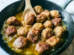 Polpette in bianco dorate e succulente, cotte in padella con cipolle dolci e un sughetto invitante. Un classico confortante.