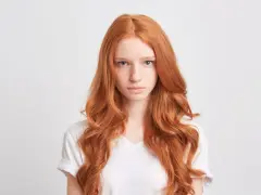 Dziewczyna z rudymi włosami, która zastanawia się nad wyborem niebieskiego szamponu na rude włosy.