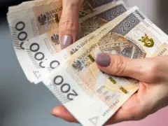 Dłoń trzyma stos banknotów 200 zł. To może być pożyczka od rodziny na nieprzewidziane wydatki.