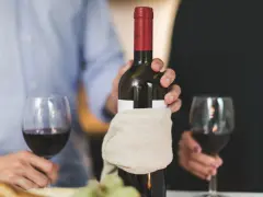 Para świętuje, trzymając butelkę wina. Pamiętaj, wino im starsze tym lepsze.