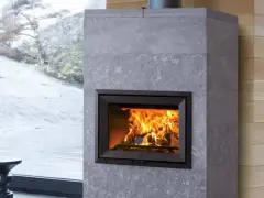 Chimenea moderna de piedra gris con fuego crepitante. Es hora de insertarleña para mantener el calor.