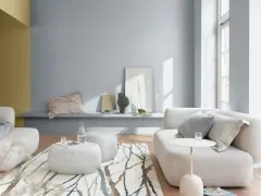 Salón moderno con sofás blancos, alfombra de ramas y paredes en pintura al agua gris y ocre.