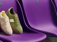 Due sneakers Clarks, una beige e una verde, sedute su sedili viola. Le Clarks calzano mezza misura in meno, perfette per un look casual.