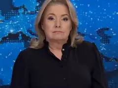 Kobieta w czarnej bluzce na tle mapy świata. Jej poważna mina sugeruje, że omawia ważne wiadomości, które wpływają na oglądalność.