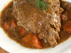 Golonka z indyka duszona w sosie własnym z marchewką, udekorowana gałązką koperku.