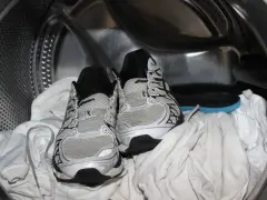 Scarpe da ginnastica pronte per essere lavate in lavatrice, insieme ad alcuni asciugamani bianchi.