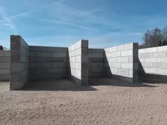 Betonowy mur oporowy w kształcie litery L, zbudowany z dużych bloków, tworzy zarys przyszłej konstrukcji.