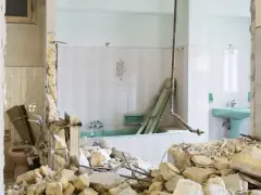 Ruiny łazienki po remoncie. Zniszczone ściany, gruz i wanna. Kara za mieszkanie w nieodebranym domu.