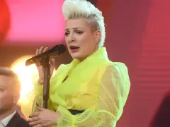 Wokalistka w neonowej kreacji śpiewa canzone d'amore, a obok niej mężczyzna z uśmiechem na twarzy.