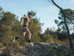 Mężczyzna w letniej odzieży sportowej pokonuje kamienisty teren, doskonaląc swój trening biegowy metodą Skarzyńskiego.