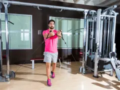 Man tränar bröstmuskler med en flyes maskin i ett modernt gym.