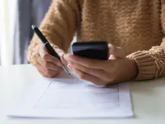 Kobieta z telefonem w dłoni wypełnia formularz, dokonując zgłoszenia darowizny online.