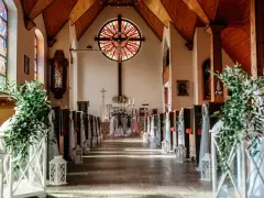 Piękna dekoracja kościoła na ślub samemu: lampiony, zielone gałązki i białe tkaniny tworzą romantyczną atmosferę.