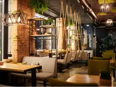 Un restaurante moderno con ladrillo visto, plantas colgantes y columpios. Un lugar acogedor que inspira lo que se necesita para abrir un restaurante.
