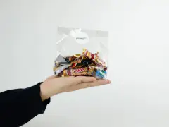En hand håller en presentkorg i cellofan fylld med choklad.