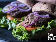 Dos deliciosas hamburguesas de lentejas con lechuga fresca, tomate y aros de cebolla morada, listas para disfrutar.