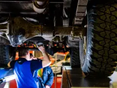 Mechanik bada podwozie terenowego Forda 4x4. Widoczna masywna oś i bieżnik opony.