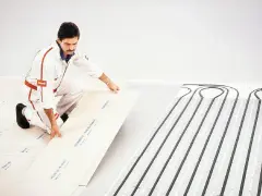 Instalator układa płyty do suchego ogrzewania podłogowego. Choć ma wiele zalet, warto znać jego wady.