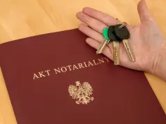 Akt notarialny i klucze na dłoni – symbol finalizacji transakcji. Komparycja dokumentu i symbolu własności.