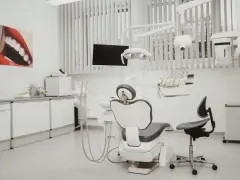 Nowoczesny gabinet stomatologiczny z fotelem, unitem i obrazem uśmiechu.