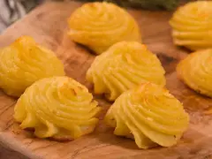 Patate duchessa dorate e invitanti, disposte su un tagliere di legno, pronte per essere gustate.