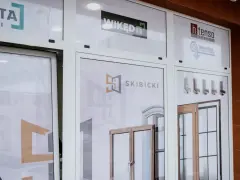 Witryna sklepowa z oknami i drzwiami, widoczne logotypy firm.