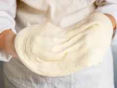 Hände halten geschmeidigen pizzateig, original rezept von einem italienischen gastronomen. Perfekt für authentische Pizza.