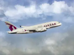 Qatar Airways Airbus A380 airplane in flight against a cloudy blue sky.